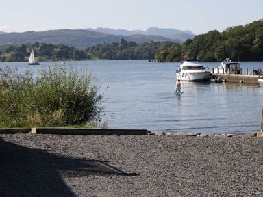 A person paddleboarding on a lake with boats and hills at Lake It Easy in Troutbeck Bridge