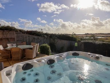 An outdoor area with a hot tub and dining table at Bay View in Weymouth