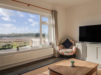 A living room with a chair and television at Bay View in Weymouth