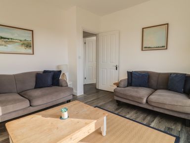 A living room with sofas and a wooden table at Bay View in Weymouth