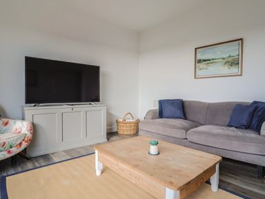 A living room with a television and sofa at Bay View in Weymouth
