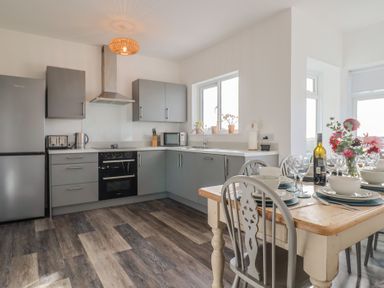 A kitchen with a table and chairs at Bay View in Weymouth