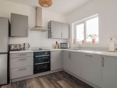 A kitchen with a refrigerator, toaster, kettle and microwave at Bay View in Weymouth