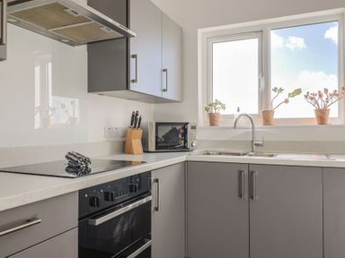 A kitchen with a sink, stove, and microwave at Bay View in Weymouth
