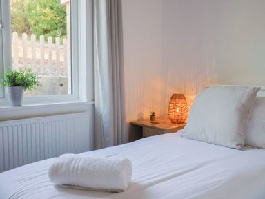 A bedroom with a bed, lamp and plant at Bay View in Weymouth