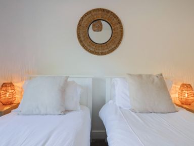 A bedroom with twin beds and a wicker mirror at Bay View in Weymouth