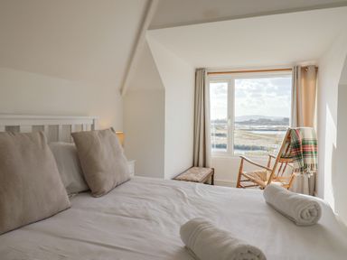 A bedroom with a bed, chair, and window at Bay View in Weymouth