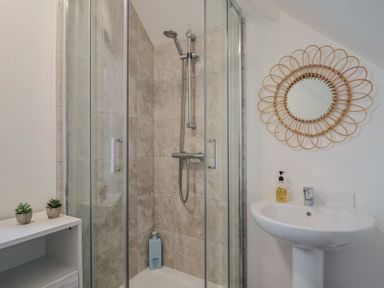 A bathroom featuring a shower, mirror, sink, and shelf at Bay View Weymouth