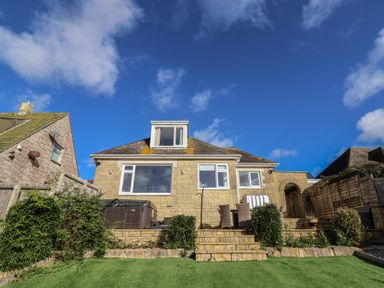 An outdoor area with a house, hot tub and landscaping at Bay View in Weymouth