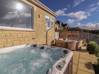 An outdoor area featuring a hot tub and dining table at Bay View in Weymouth