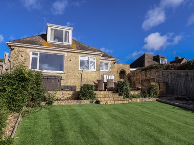 A garden with a house and lawn at Bay View in Weymouth