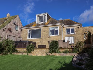 A house with a hot tub and patio furniture in the garden at Bay View in Weymouth