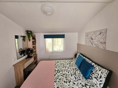 A bedroom with a bed, mirror, and shelf at 