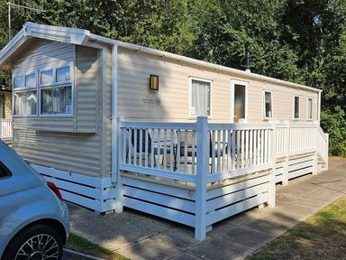 A mobile home with a deck and railing at a park location