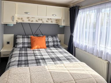 A bedroom with a bed and windows at 3 Bedroom Seafront Caravan, Sleeps 6 with Parking