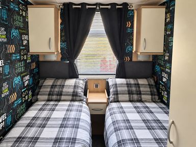 A bedroom with two single beds and gaming-themed wallpaper at 3 Bedroom Seafront Caravan, Sleeps 6 with Parking