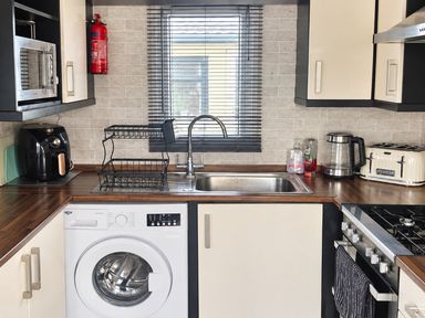 A kitchen with a washing machine and stove at 3 Bedroom Seafront Caravan, Sleeps 6 with Parking