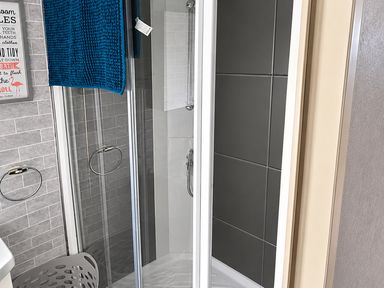 A bathroom with a shower and towel on the rack at 3 Bedroom Seafront Caravan, Sleeps 6 with Parking