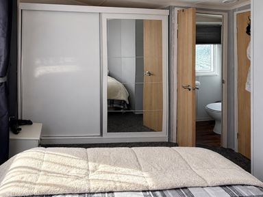 A bedroom with a bed and a mirror at 3 Bedroom Seafront Caravan, Sleeps 6 with Parking