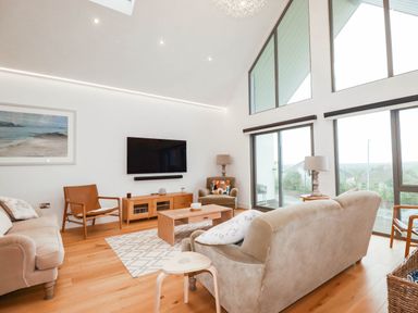 A living room with a sofa, coffee table, television and armchair at 1 Endellion View Wadebridge