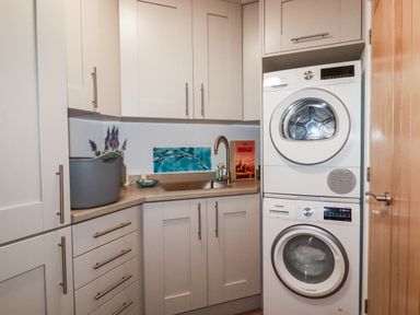A laundry room with a washing machine and tumble dryer at 1 Endellion View Wadebridge
