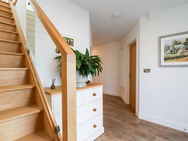 A hallway with a staircase and a drawer unit at 1 Endellion View Wadebridge