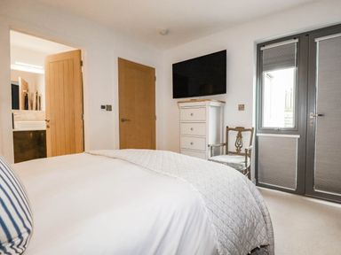 A bedroom with a bed, dresser, chair, and tv at 1 Endellion View Wadebridge