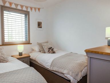 A bedroom with two beds and a window at 1 Endellion View Wadebridge