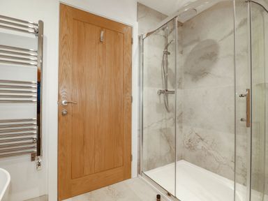 A bathroom with a shower and door at 1 Endellion View Wadebridge