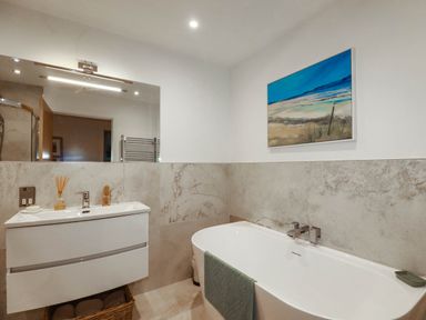 A bathroom with a bathtub and sink at 1 Endellion View Wadebridge
