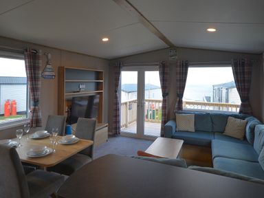 A living room with a dining set and television at Perran Sands Holiday Park - 615 Chy-an-Mor in Perranporth