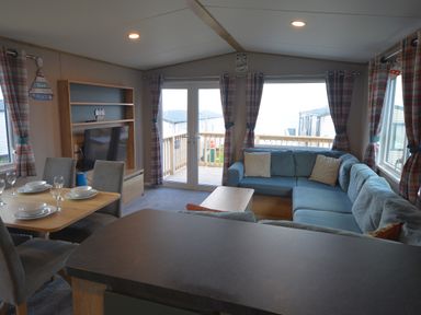 A living room with a sofa and dining table at Perran Sands Holiday Park - 615 Chy-an-Mor Perranporth