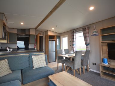 A living room with a couch, table, and chairs at Perran Sands Holiday Park - 615 Chy-an-Mor Perranporth