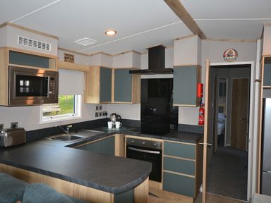 A kitchen with appliances and cabinets at Perran Sands Holiday Park - 615 Chy-an-Mor, Perranporth