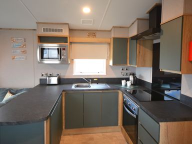 A kitchen with a sink, microwave, and countertop at Perran Sands Holiday Park - 615 Chy-an-Mor in Perranporth