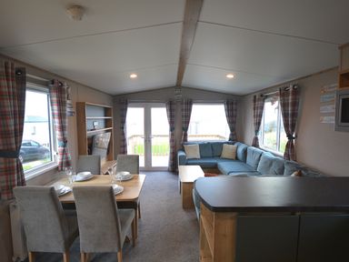 A living room with a sofa and dining table at Perran Sands Holiday Park - 615 Chy-an-Mor in Perranporth