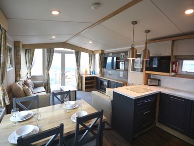 A living room with a dining area and kitchen at Perran Sands Holiday Park - 620 Chy An Mor in Perranporth