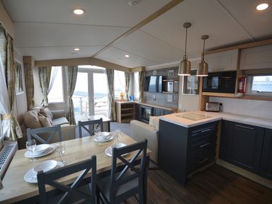 A kitchen with dining area and seating at Perran Sands Holiday Park - 620 Chy An Mor in Perranporth