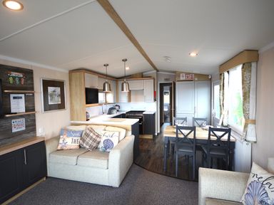 A living room with a sofa and dining area at Perran Sands Holiday Park - 620 Chy An Mor in Perranporth