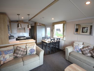 A living room with a dining area and kitchen at Perran Sands Holiday Park - 620 Chy An Mor Perranporth