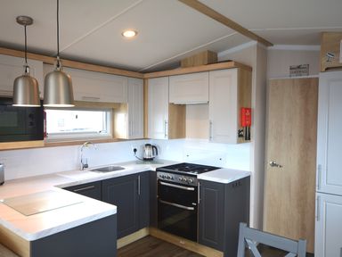 A kitchen with cabinets and appliances at Perran Sands Holiday Park - 620 Chy An Mor Perranporth