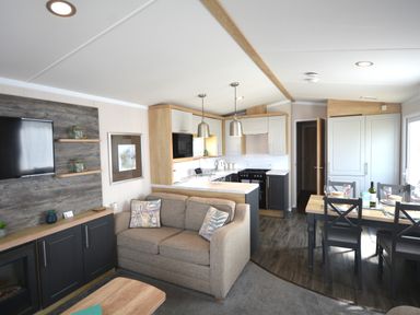 A living room with a sofa and kitchen in Perran Sands Holiday Park - 620 Chy An Mor Perranporth