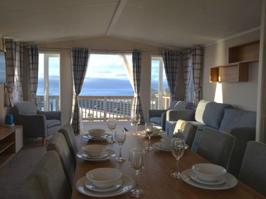 A living room with a sofa and dining table at Perran Sands Holiday Park - 621 Chy-an-Mor Perranporth