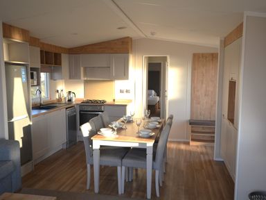 A kitchen with a dining table and chairs at Perran Sands Holiday Park - 621 Chy-an-Mor Perranporth