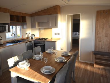A kitchen with dining table set for meal at Perran Sands Holiday Park - 621 Chy-an-Mor Perranporth