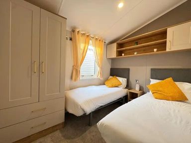A bedroom with two beds and a wardrobe at Perran Sands Holiday Park - 621 Chy-an-Mor, Perranporth