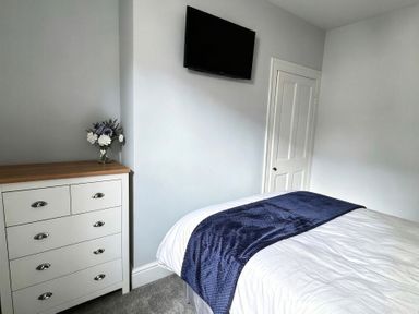 A bedroom with a bed, dresser, and television at Jacks Place in Whitby