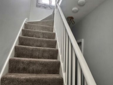 A staircase with carpet and handrail at Jacks Place in Whitby