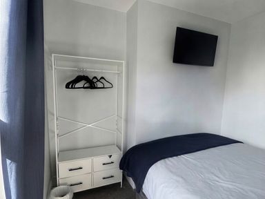 A bedroom with a bed, drawer unit, and television at Jacks Place in Whitby