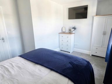 A bedroom with a bed, dresser, mirror, and television at Jacks Place in Whitby
